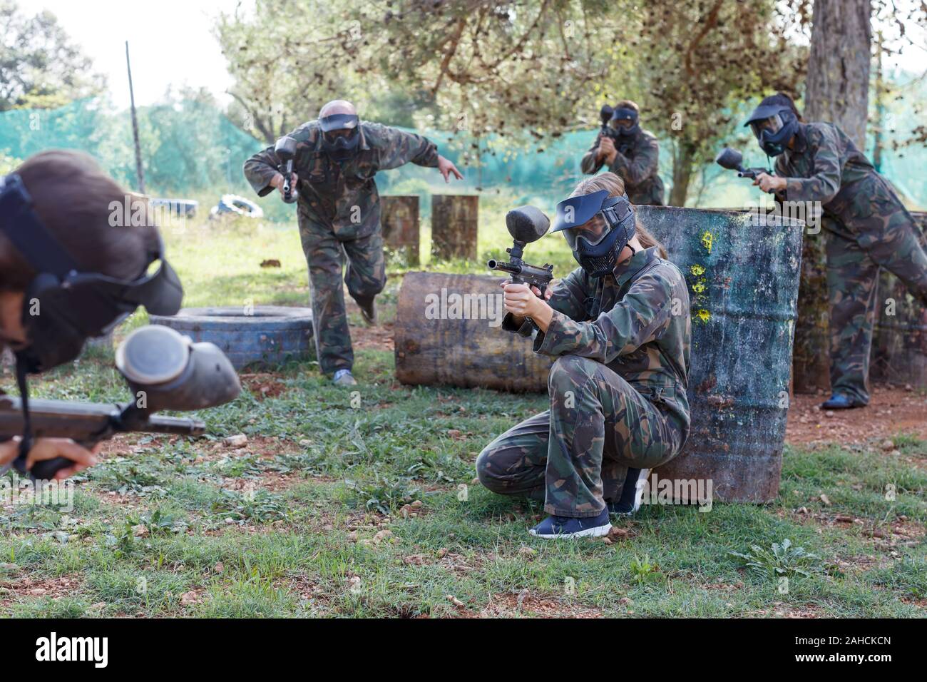 Female Paintball Player In Full Equipment Aiming With Gun In Shootout