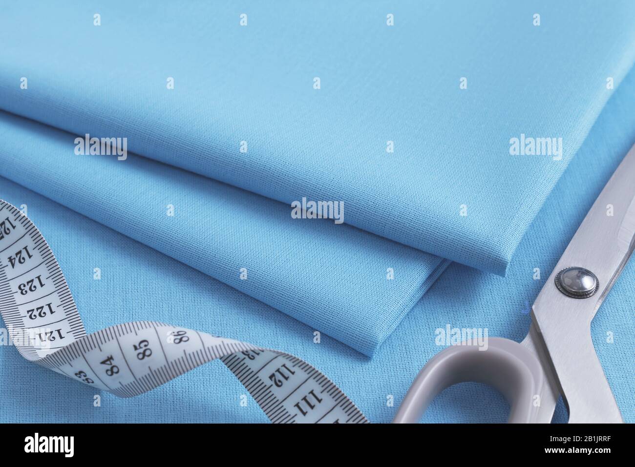 A Stack Of Folded Blue Fabric Sewing Scissors And A Twisted White