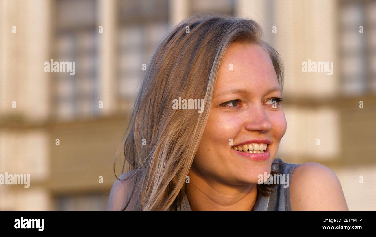 Laughing Blonde Woman Sitting Outdoors Stock Photo Alamy