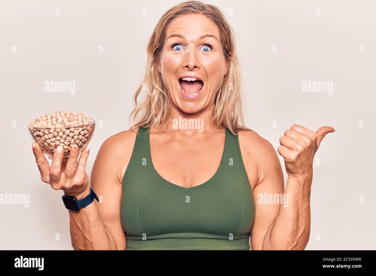 Middle Age Caucasian Blonde Woman Holding Chickpeas Bowl Pointing Thumb