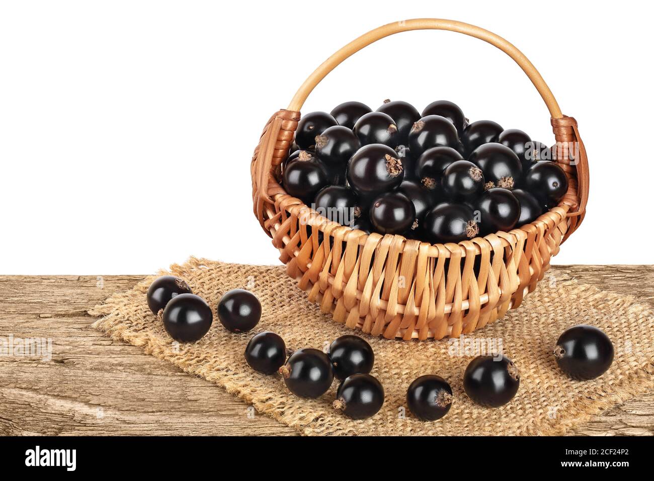 Black Currant In Wicker Basket On Wooden Table Isolated On White