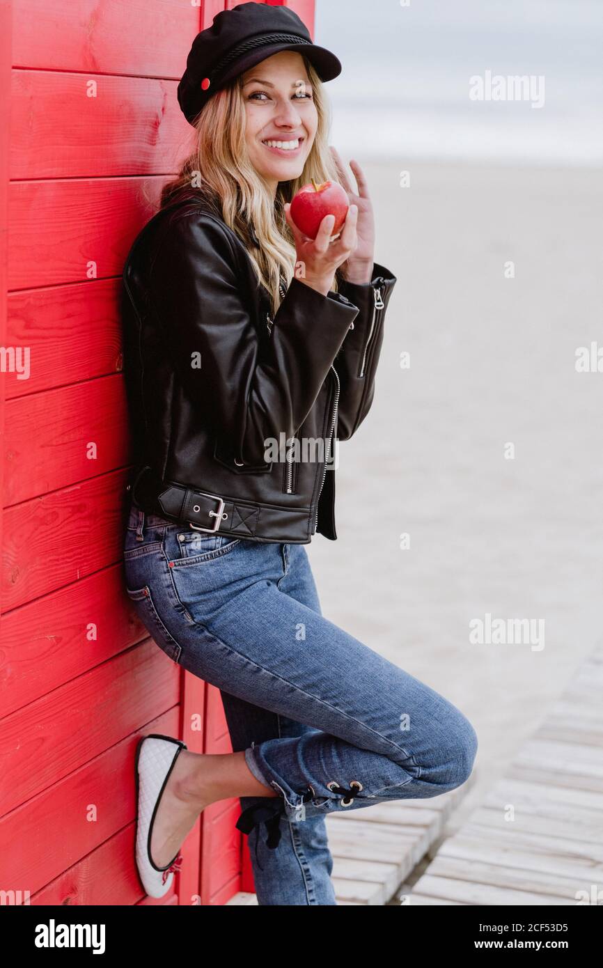 Trendy Long Haired Blonde Woman In Black Cap And Leather Jacket Smiling