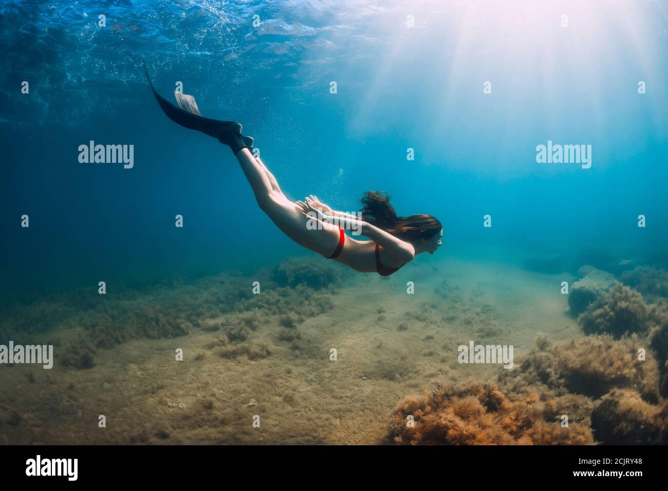 Freediver Slim Woman In Bikini Glides In Blue Sea And Sun Rays