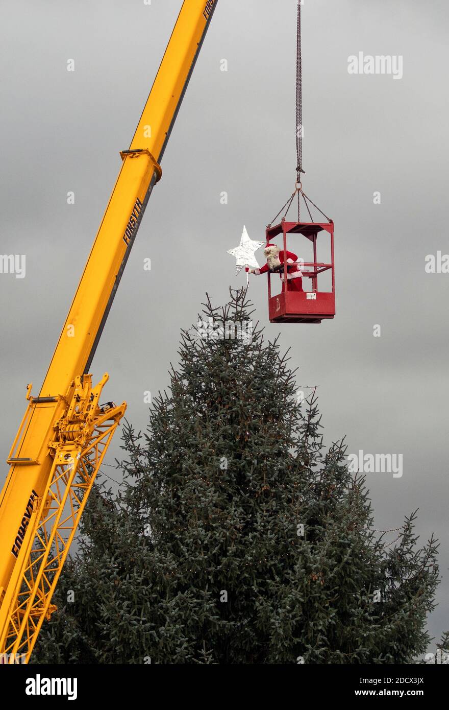 Santa Claus Uses A Crane To Place The Star On Top Of The Christmas Tree