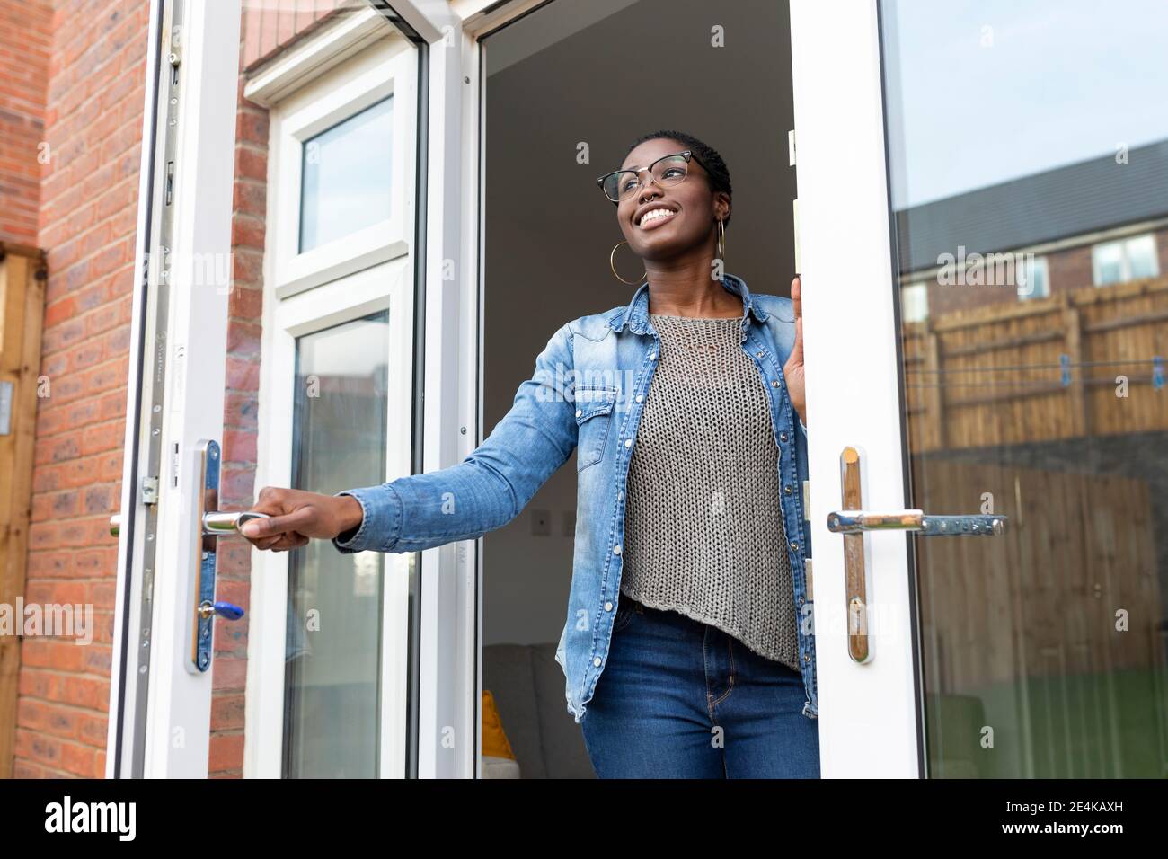 Smiling Woman Opening House Doors Stock Photo Alamy