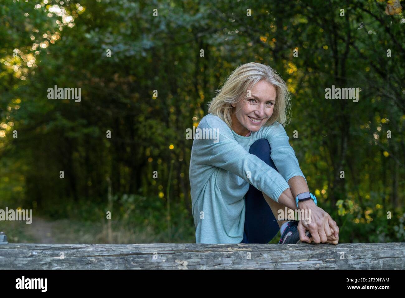 Portrait Of Smiling Mature Woman Stretching Her Leg In Forest Stock