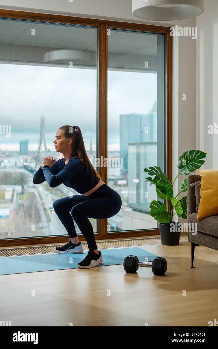 Slim Brunette Woman In Turquoise Jumpsuit In Squat Position Stock Photo