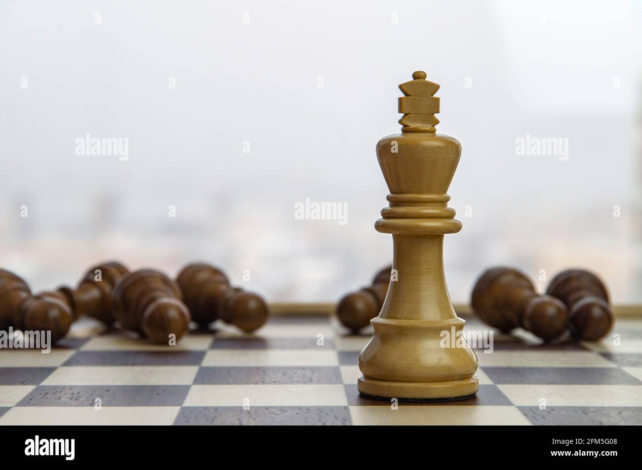 White Chess King Among Lying Down Black Pawns On Chessboard Concept