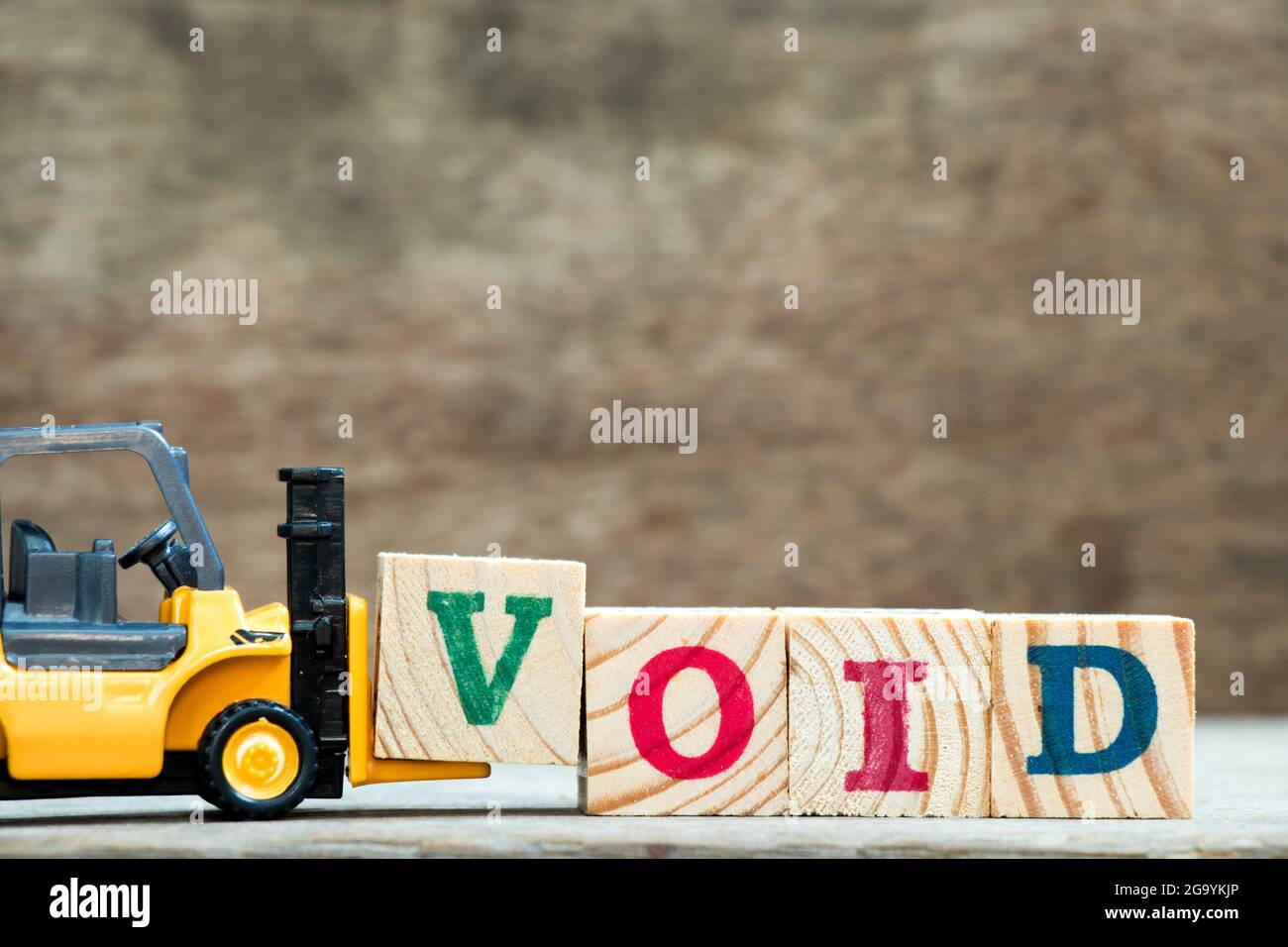 Yellow Toy Forklift Hold Letter Block V To Complete Word Void On Wood