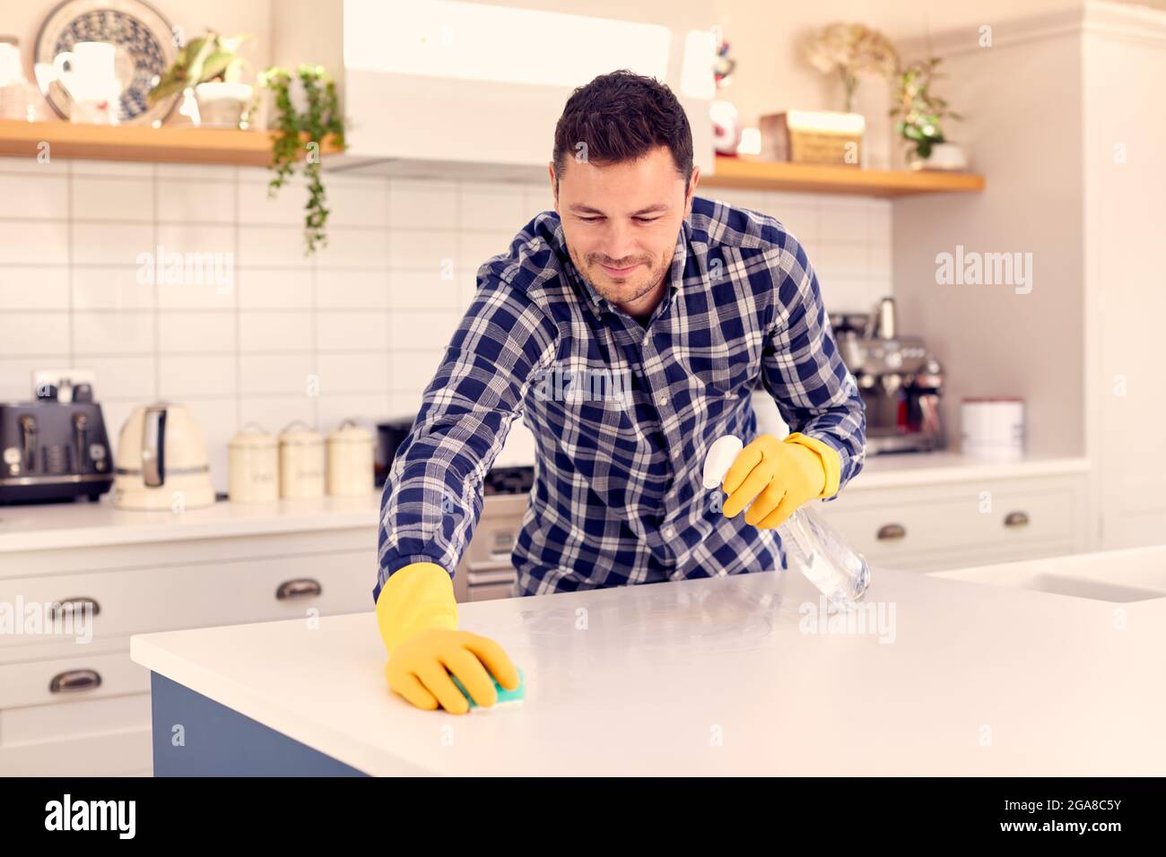 Man At Home In Kitchen Doing Housework And Cleaning Counter Surface