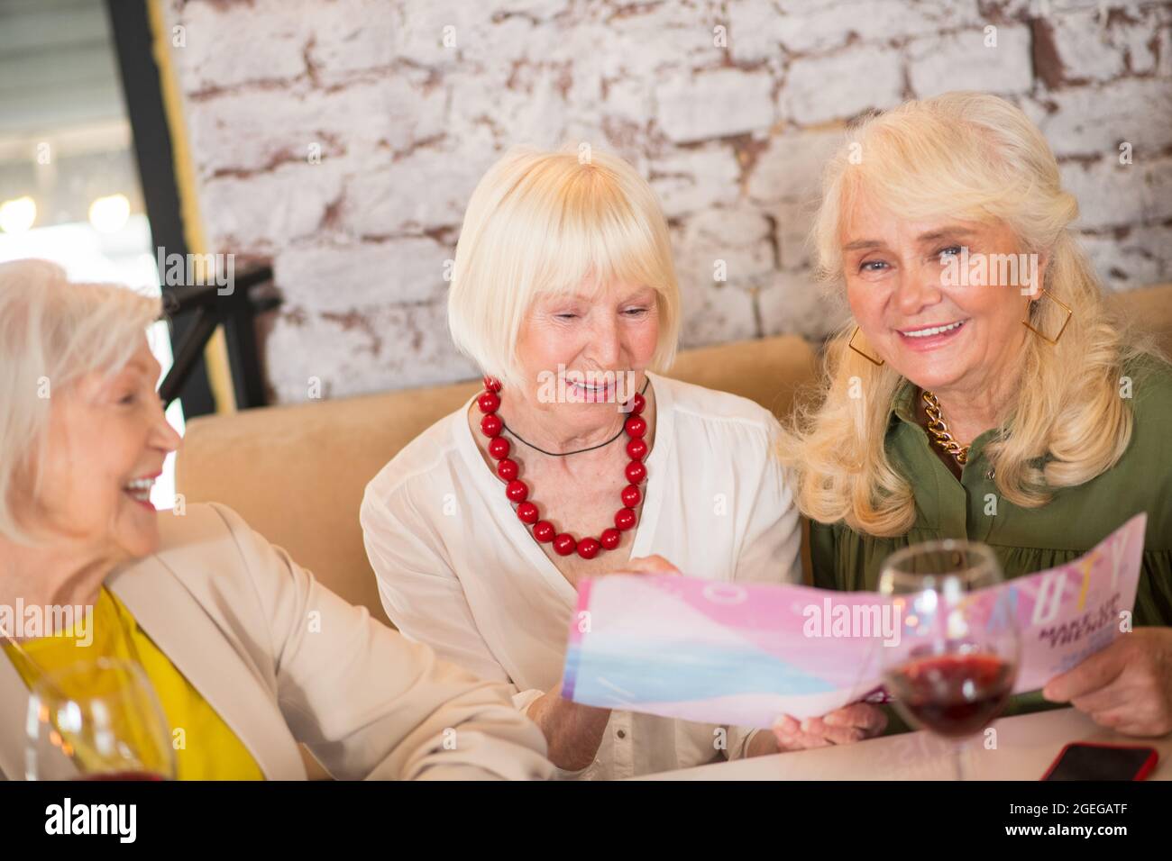Three Mature Women Sitting At The Table And Looking Excited Stock Photo Alamy
