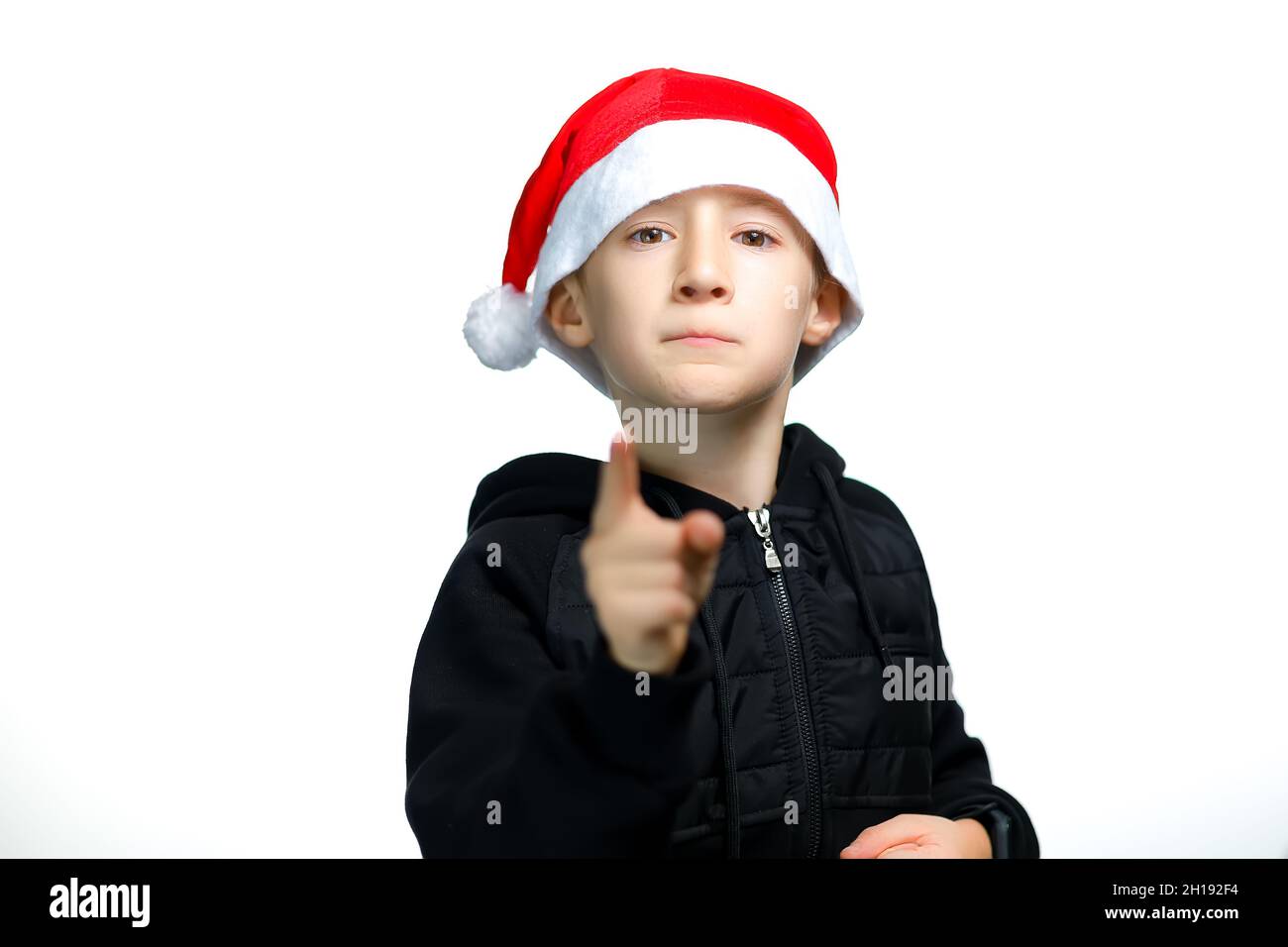 A Boy In A Red Santa Hat Points His Index Finger At The Camera Stock