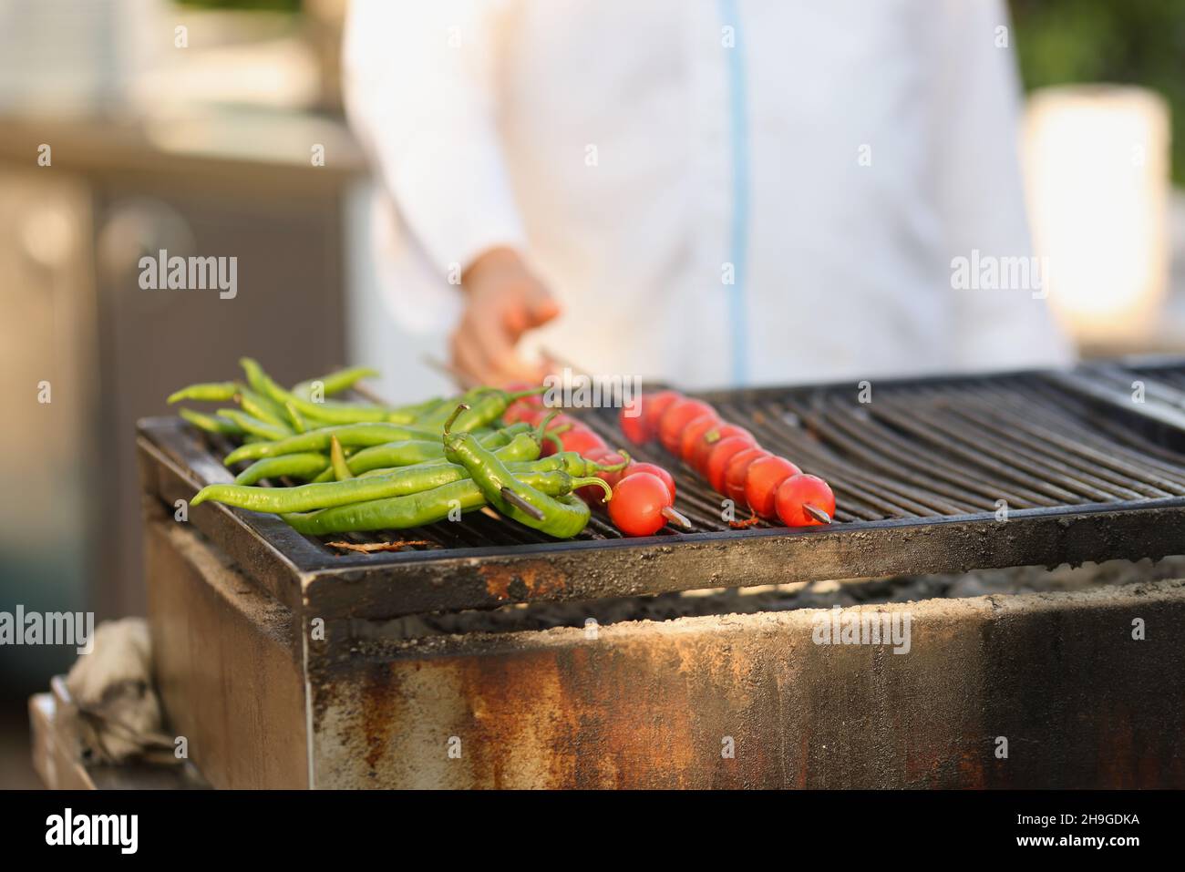 Amateur Chef Frying Fresh Tomatoes And Green Pepper On Grill On Open