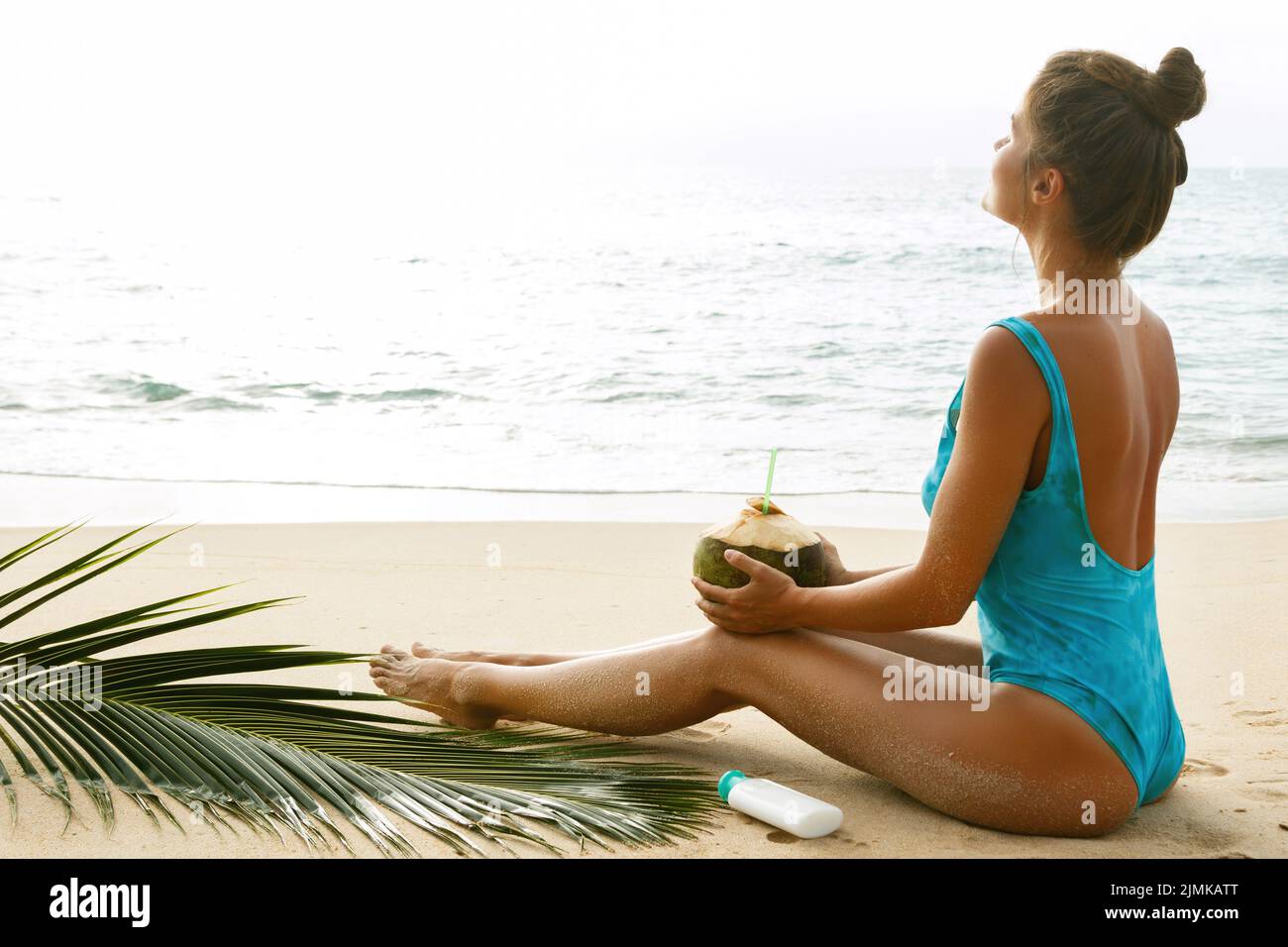 Woman Is Sunbathing On The Beach With A Coconut Drink Stock Photo Alamy