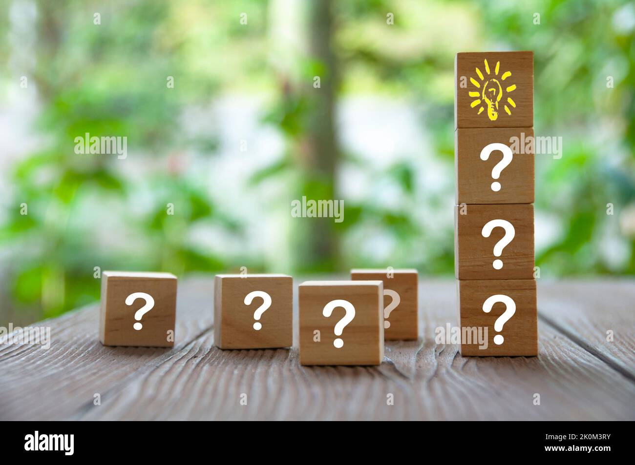 Wooden Cube Block With Light Bulb Surrounded By Questions Marks