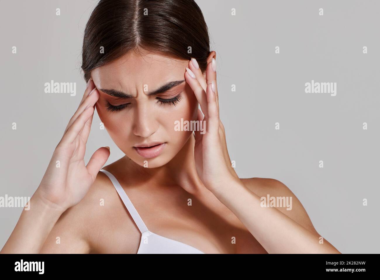 Brunette Girl Holding Her Head And Having Strong Headache Stock Photo