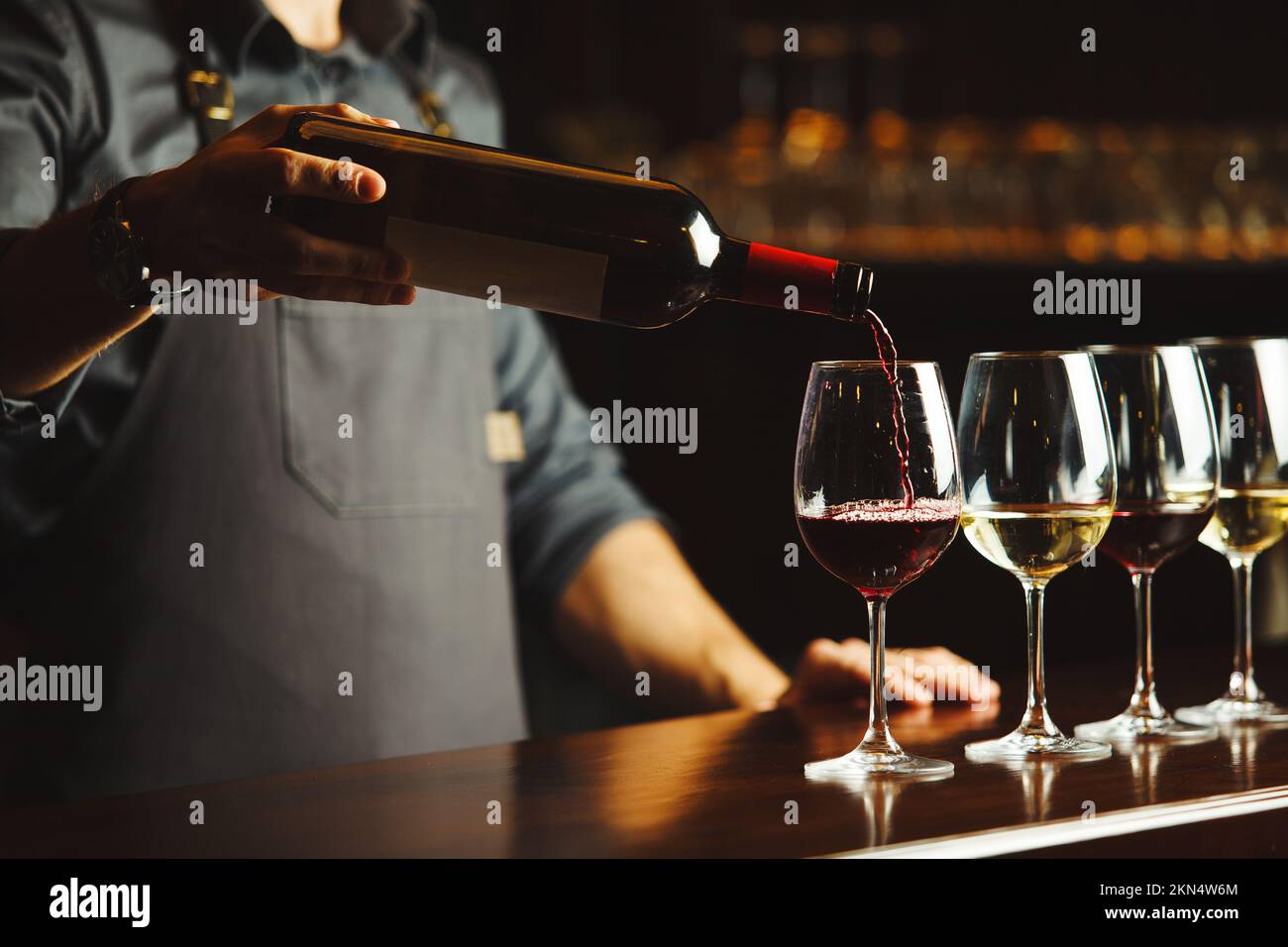 Bartender Pours Red Wine In Glasses On Wooden Bar Counter Stock Photo