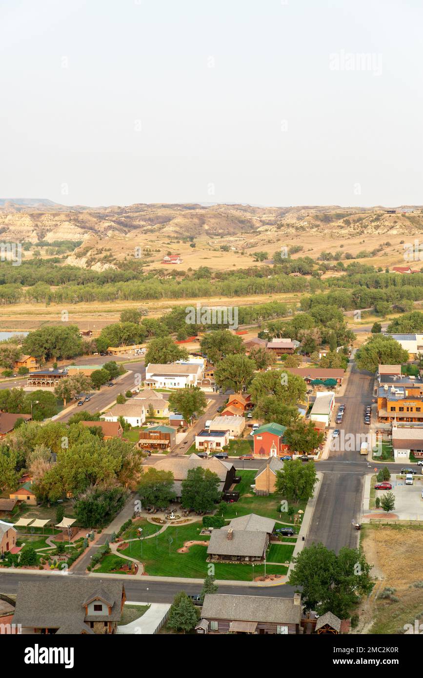 An Aerial Of A Small Town Surrounded By The Green Trees With Hills In