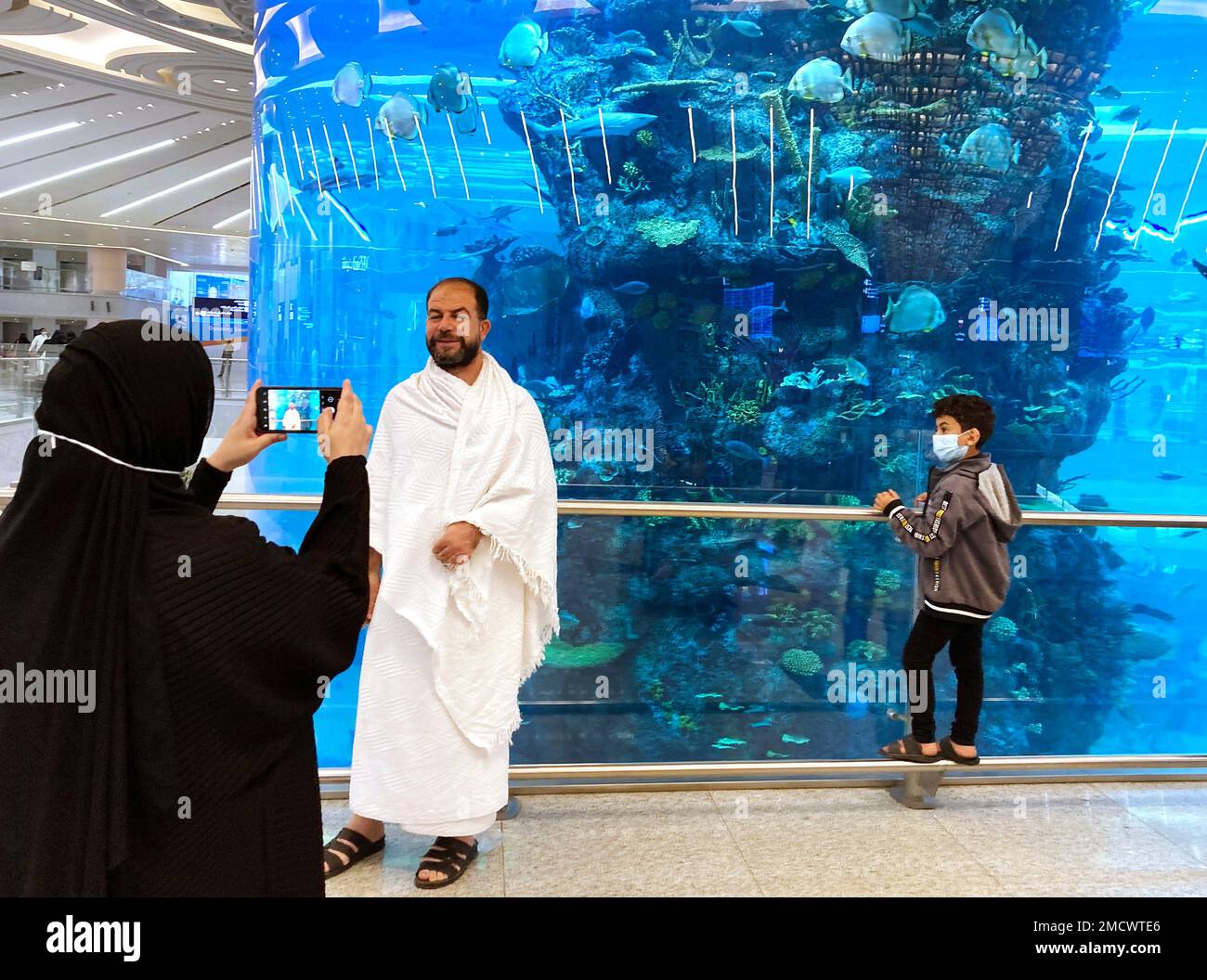 A Pilgrim Poses For A Picture In Front Of Of A Giant Aquarium At The