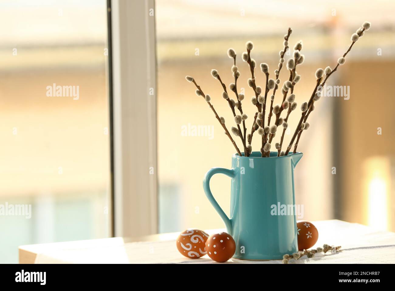 Jug With Pussy Willow Branches And Easter Eggs On Table Near Window