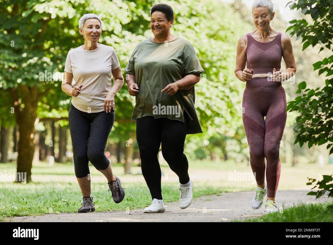 Full Length Portrait Of Three Active Senior Women Jogging In Park