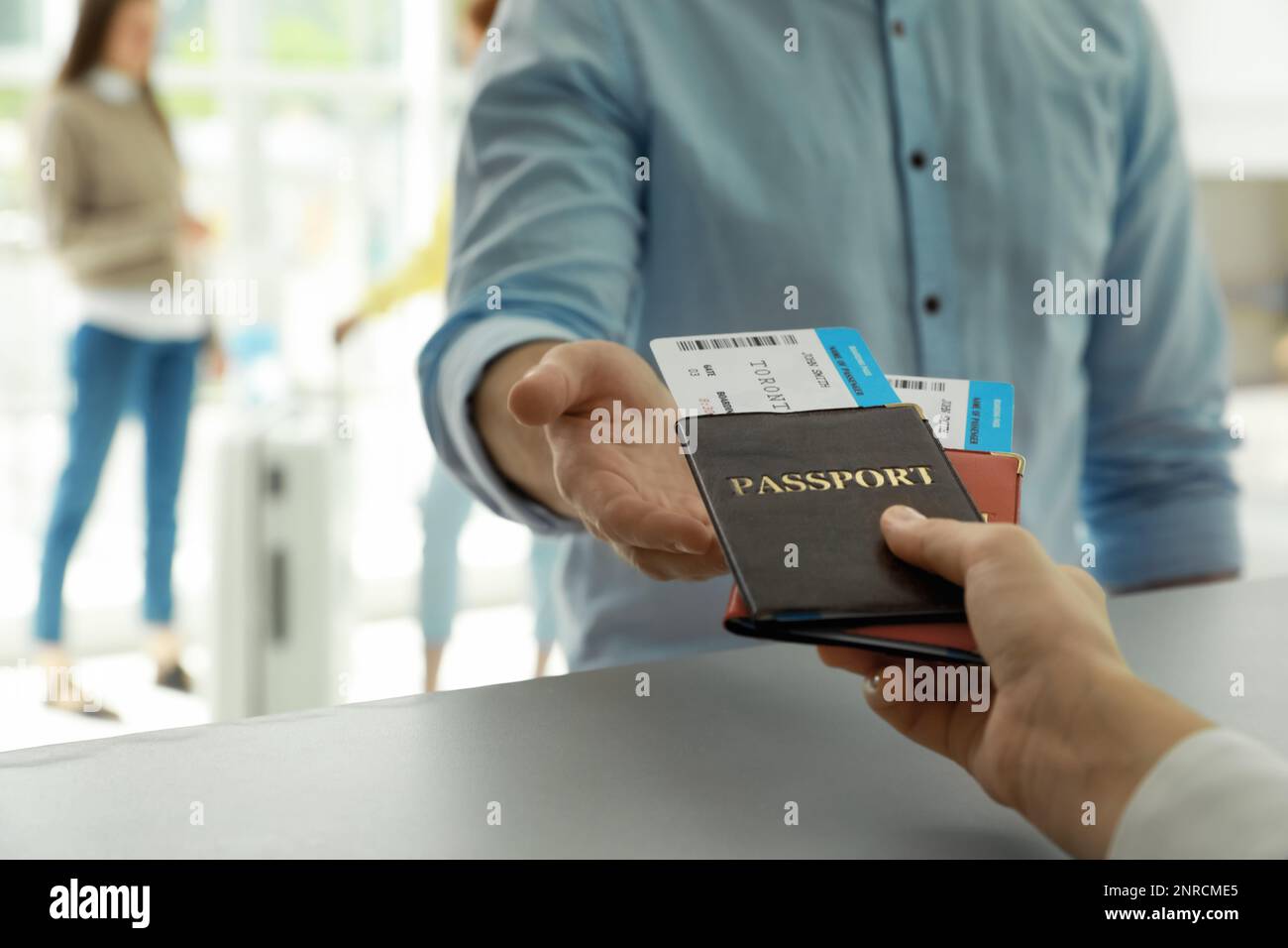 Agent Giving Passports And Tickets To Man At Check In Desk In Airport