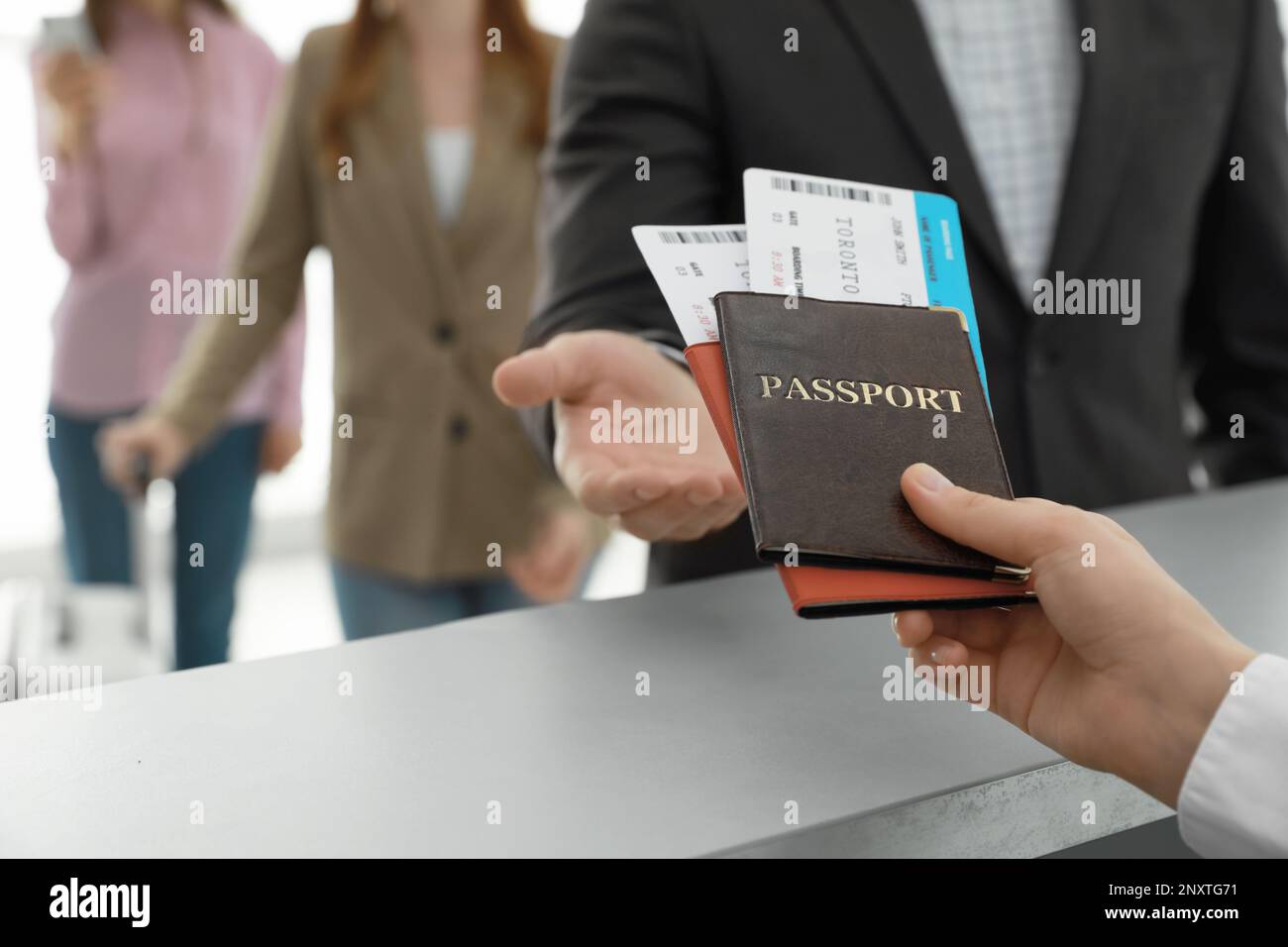 Agent Giving Passports And Tickets To Man At Check In Desk In Airport