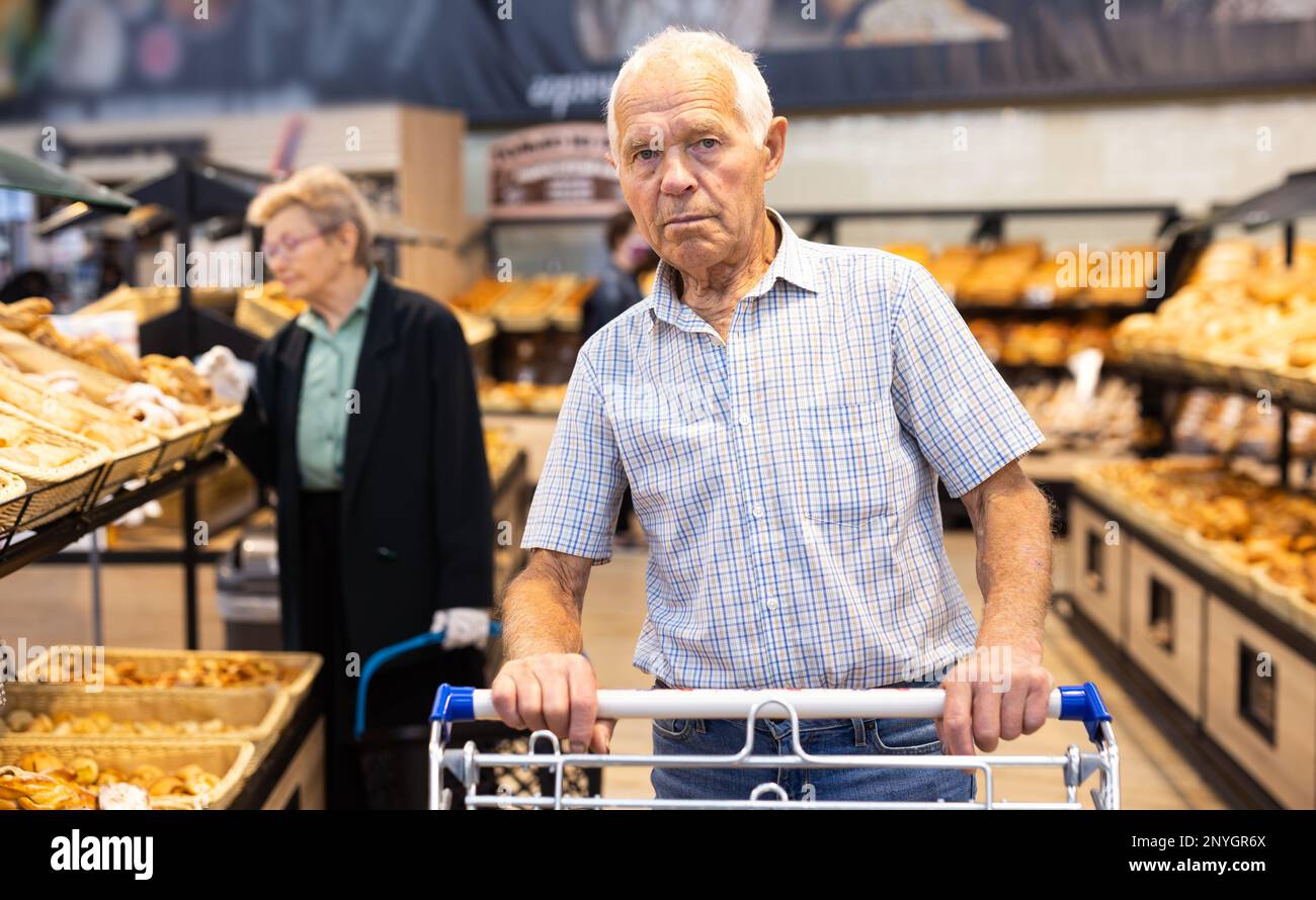 Older Man Shopping Buns And Bread In Bakery Section Of Supermarket