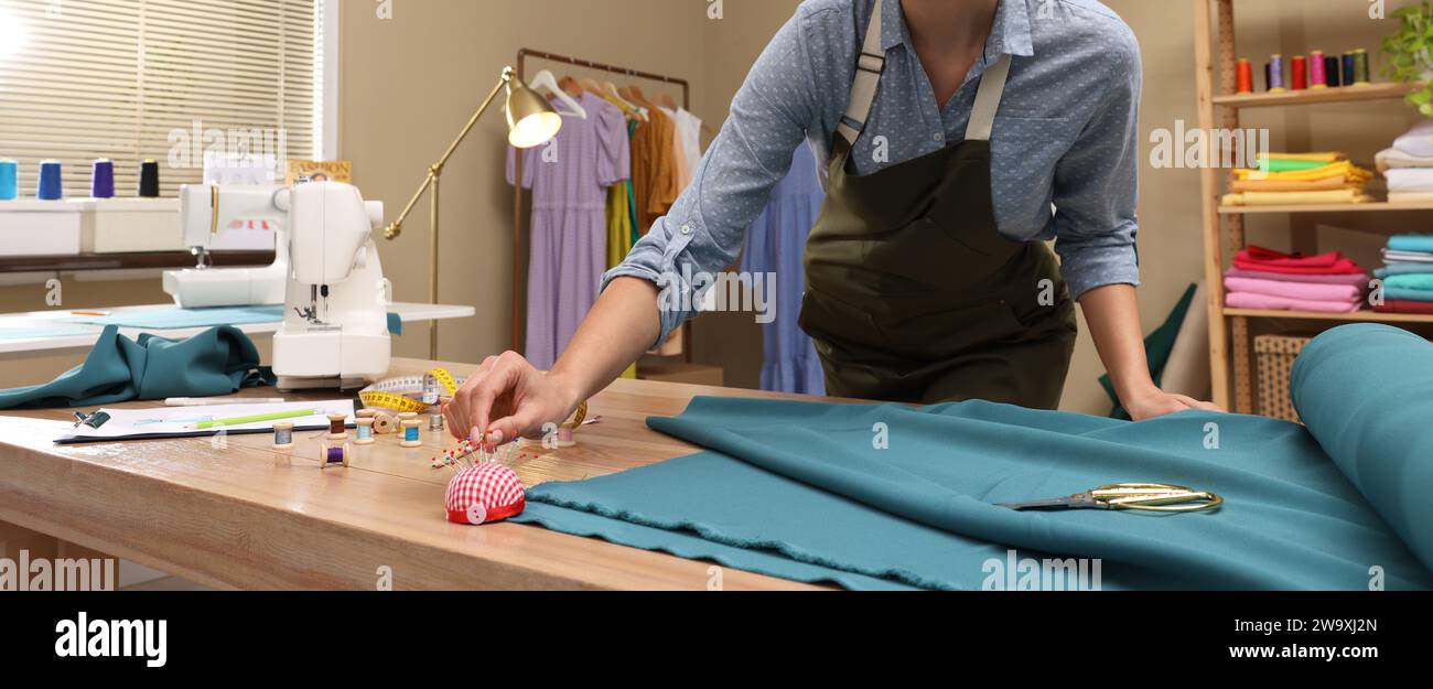 Dressmaker Taking Pin From Cushion In Workshop Closeup Banner Design