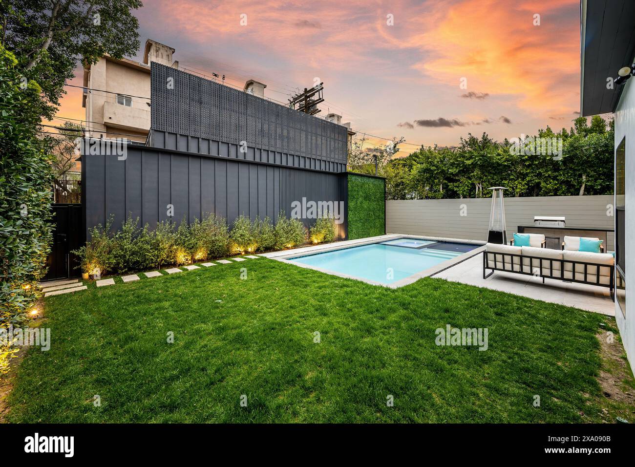 A Backyard Featuring A Pool And Fenced Area With Lush Green Grass Stock