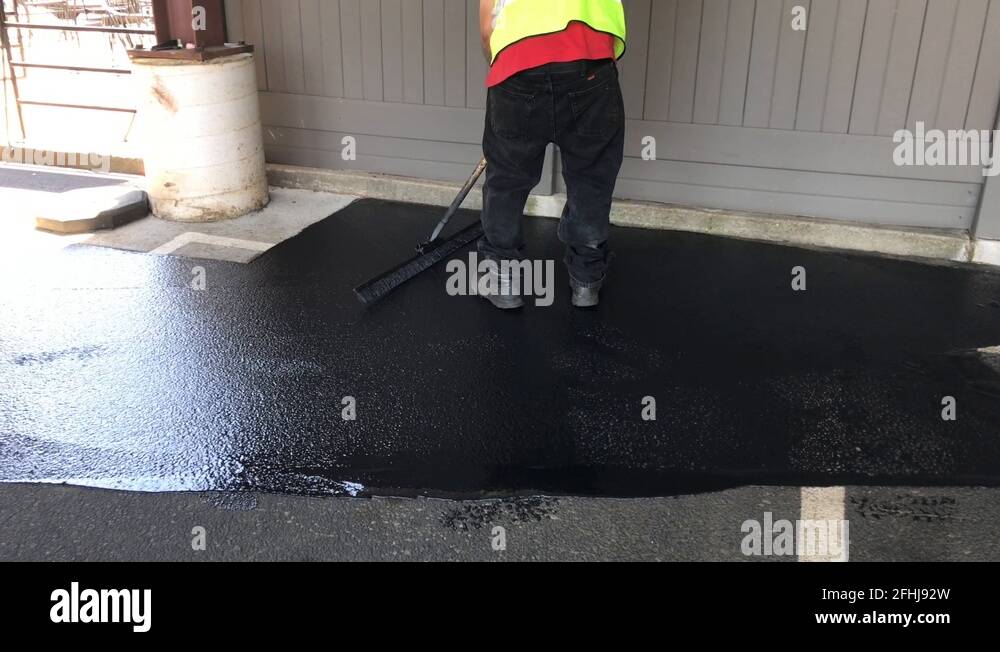 A Man Applying Seal Coating On Parking Lot Pavement Stock Video Footage