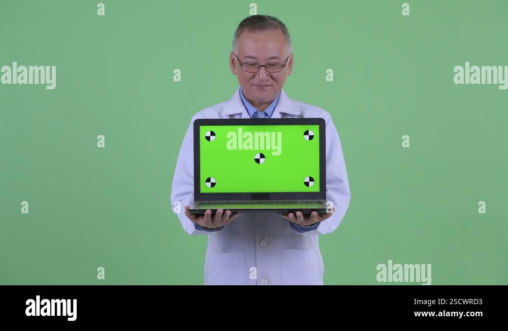 Happy Mature Japanese Man Doctor Talking While Showing Laptop Stock