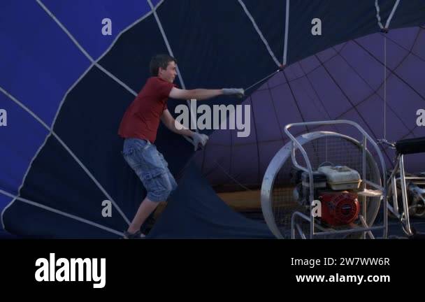 A Man Lifts Up A Huge Balloon At A Balloon Festival Blowing Up Hot Air Balloons Flame Rising