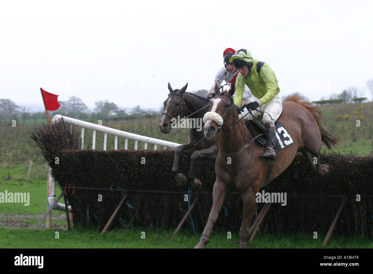 two jockeys and horses jump over a fence at Maralin Point to Point Stock Photo, Royalty Free