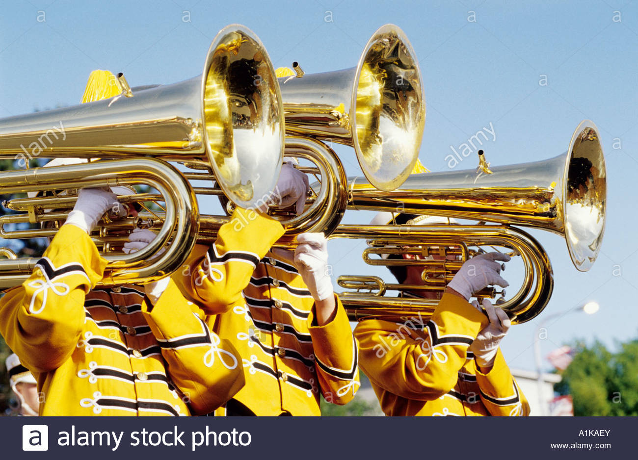 three-people-in-yellow-uniform-playing-trumpets-in-brass-band-A1KAEY.jpg