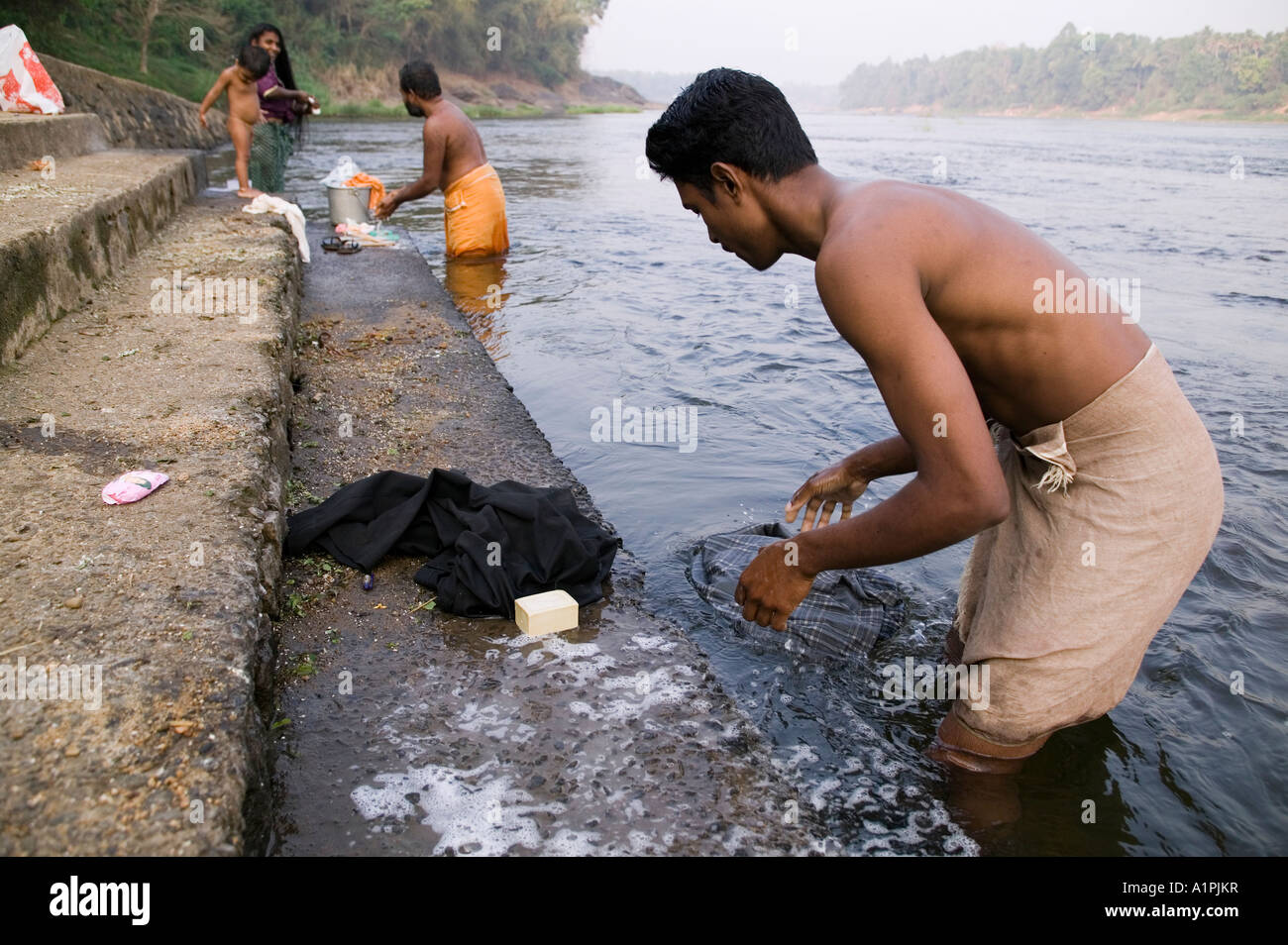 A man and a family washing clothes in the river in Kerala India Stock
