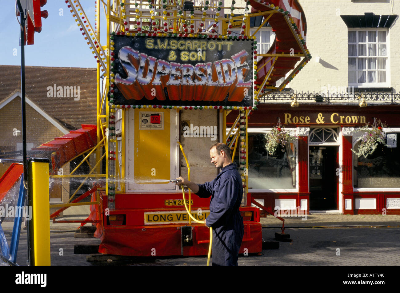 Man Setting Up At Fun Fair .cleaning Ride By Spraying Water From Stock
