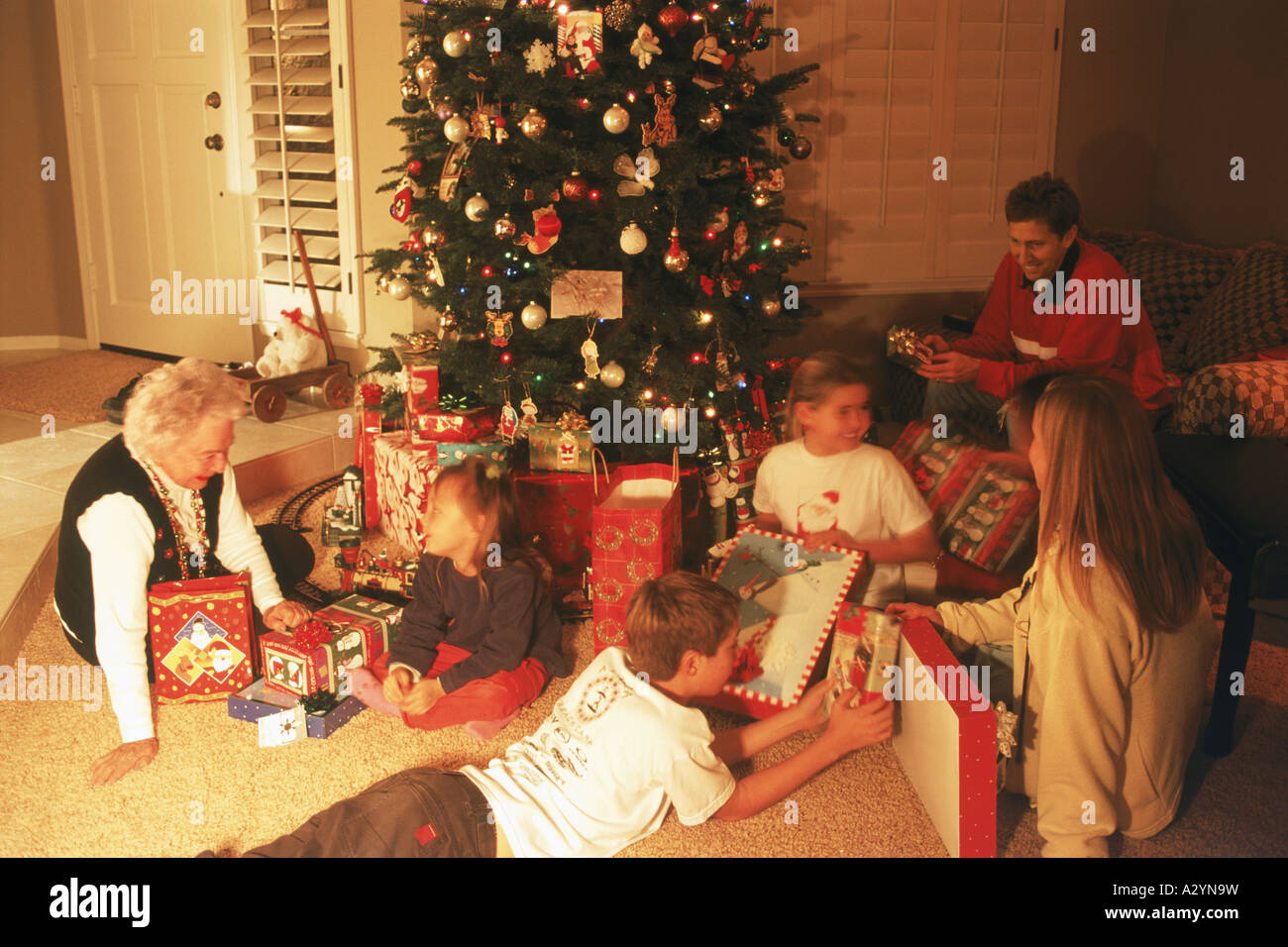 family and friends around christmas tree at home family and friends around christmas tree at home
