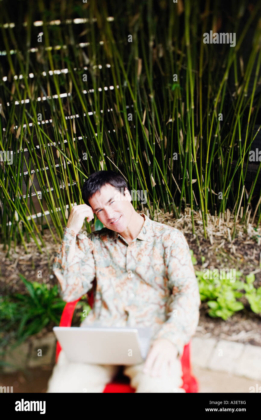 Portrait Of A Mature Man Sitting On A Chair With A Laptop On His Lap