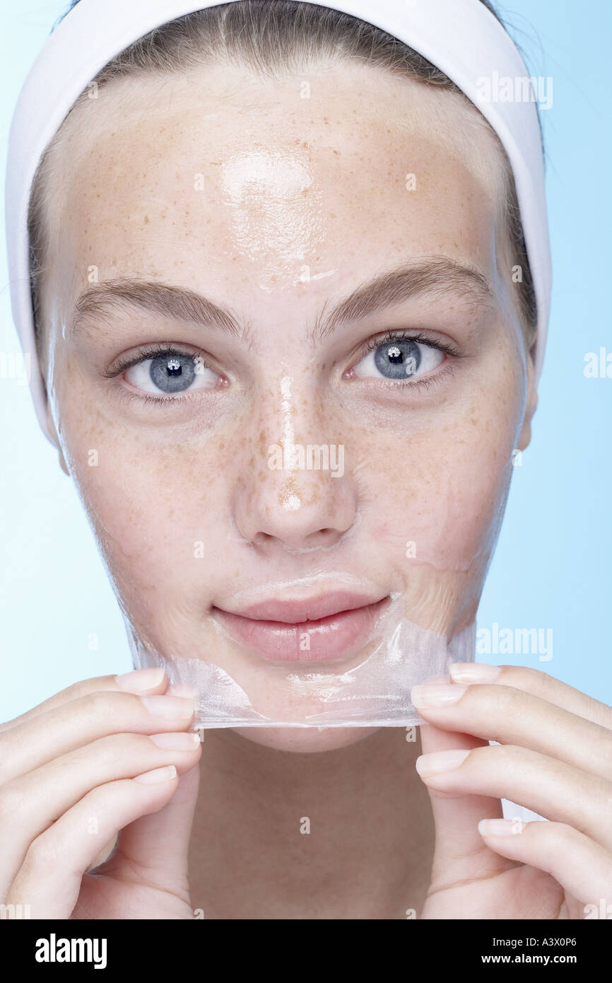 A young woman peeling off a face mask Stock Photo, Royalty Free Image