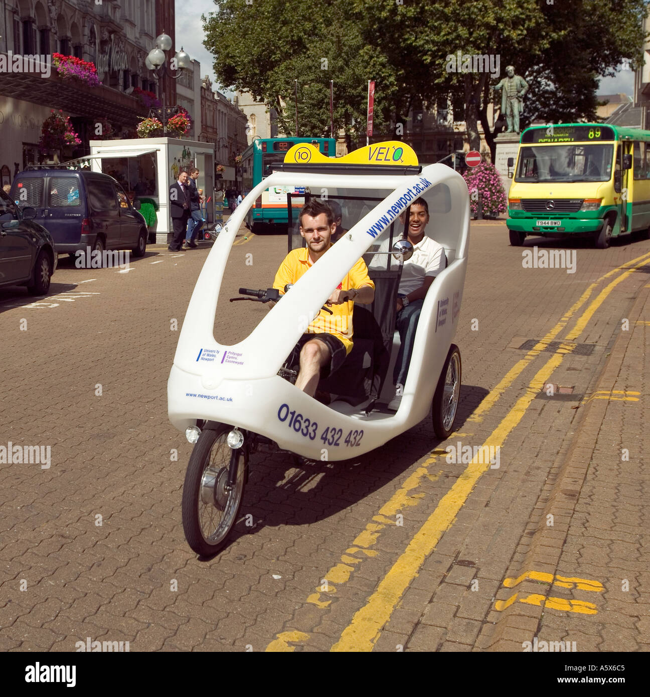Tricycle taxi with public transport bus Cardiff South Wales UK Stock