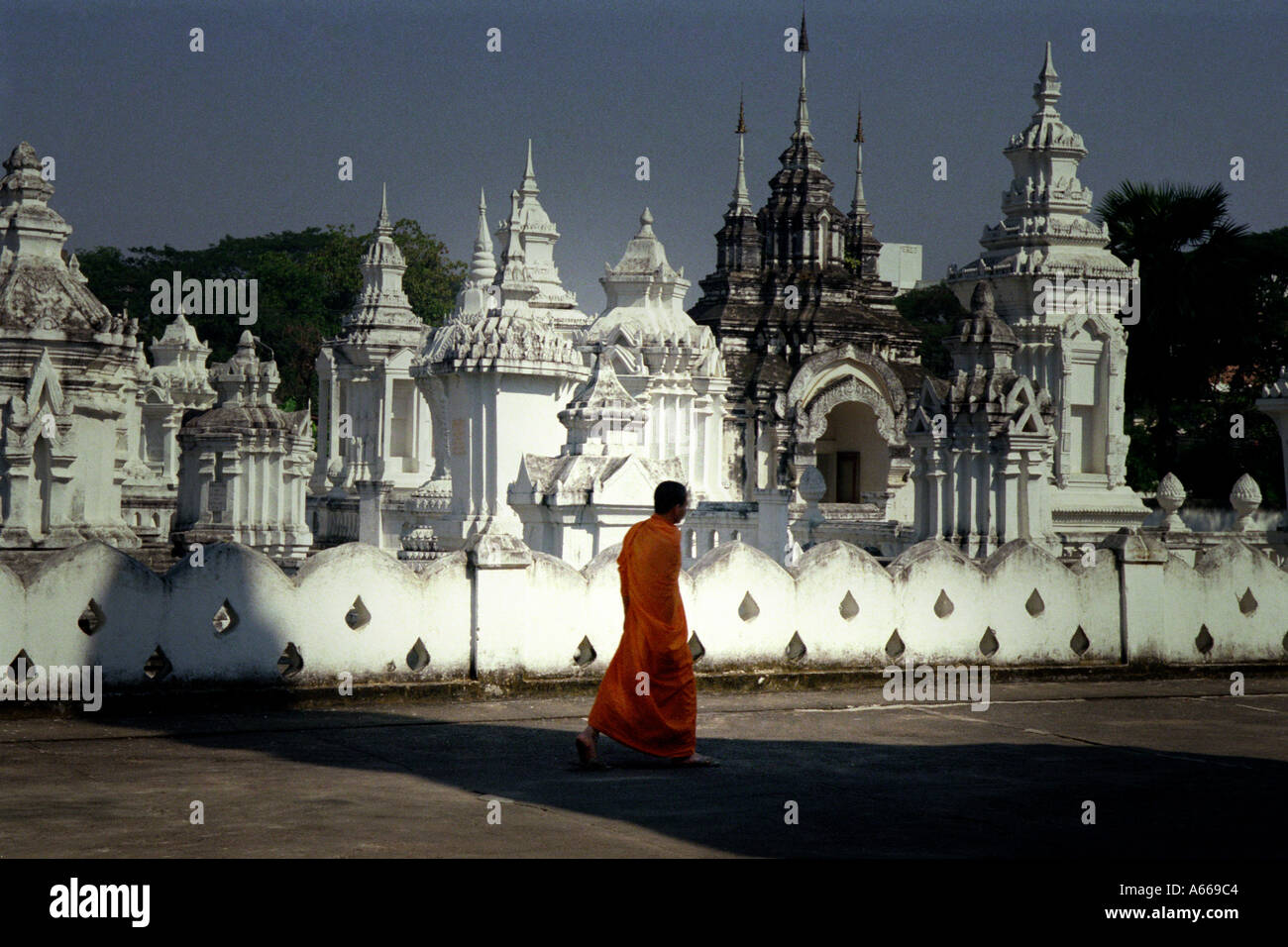 Buddhist Monk Walks By A Group Of Pantheons In Wat Suan Dok In Chiang