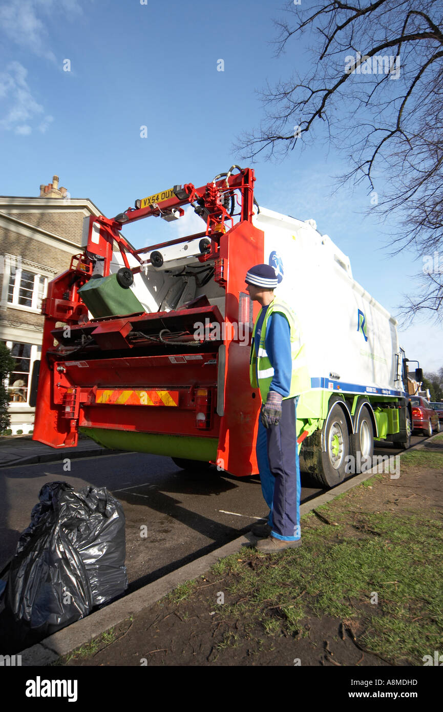 Waste rubbish or trash lorry or truck lifting green bin with man in