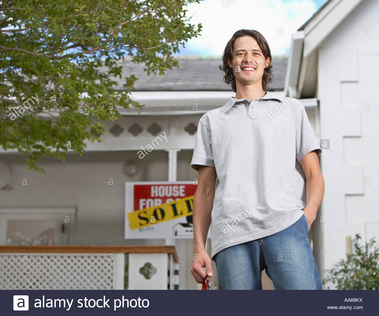 Man With Keys Standing In Front Of House Sold Sign Man With Keys Standing In Front Of House Sold Sign