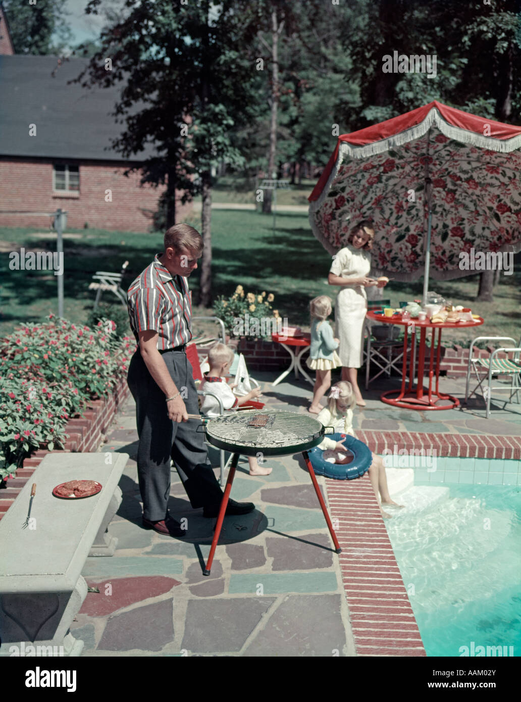 1950s SUBURBAN FAMILY IN BACKYARD BY POOL WITH BAR-B-CUE NOSTALGIA