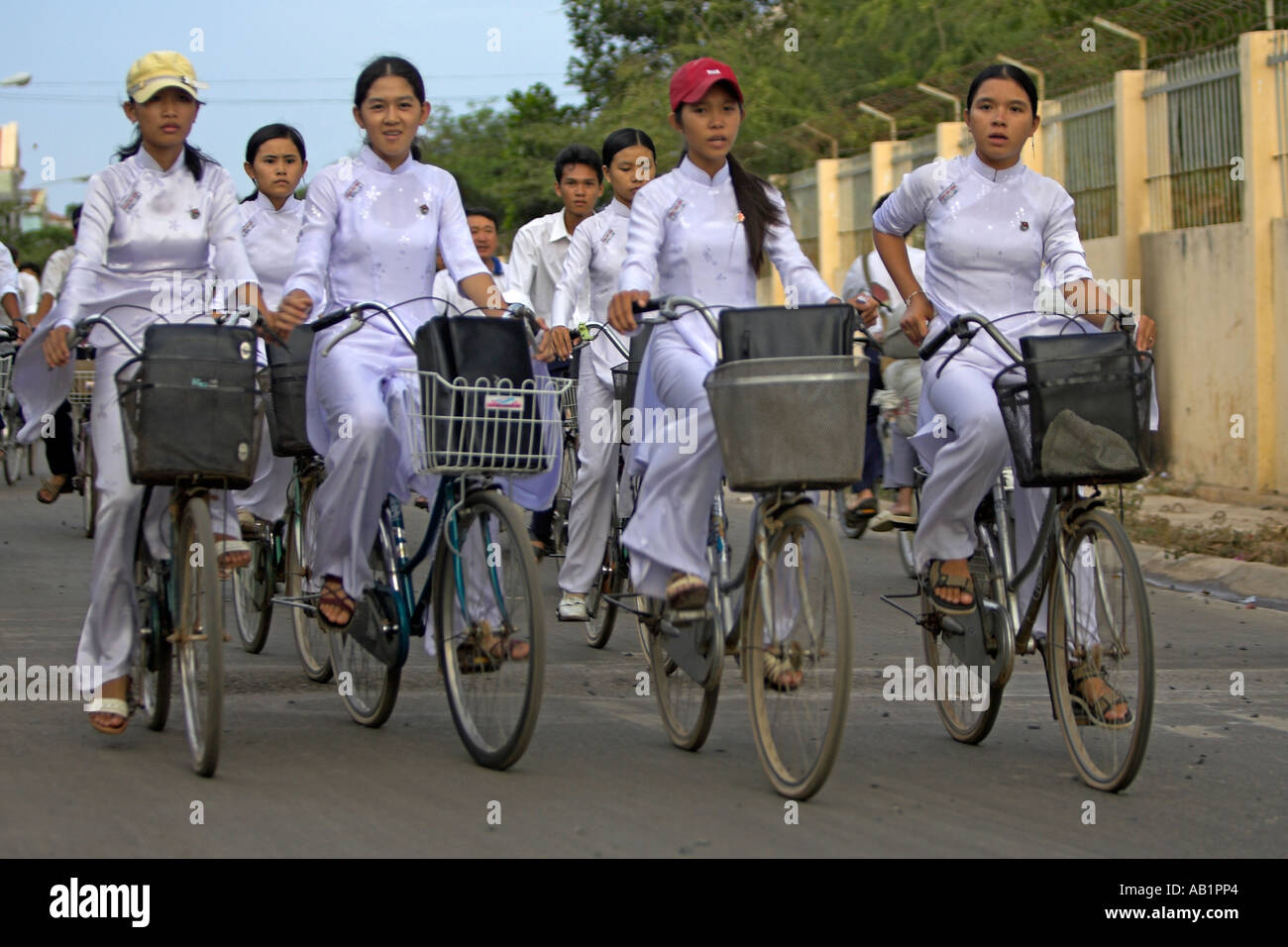 High school girls in traditional white ao dai uniform ride home with