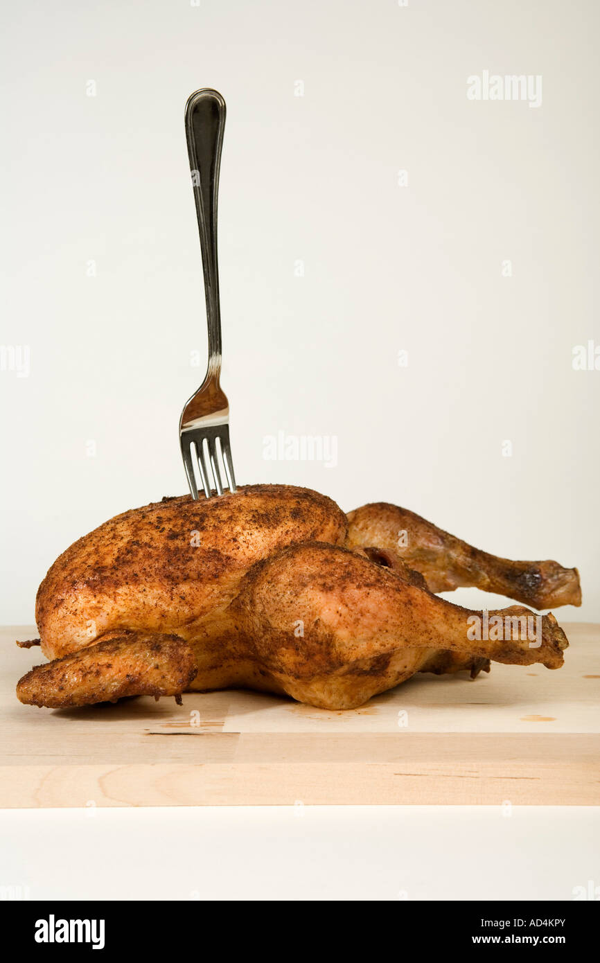 A fork stuck in a roast chicken Stock Photo, Royalty Free Image