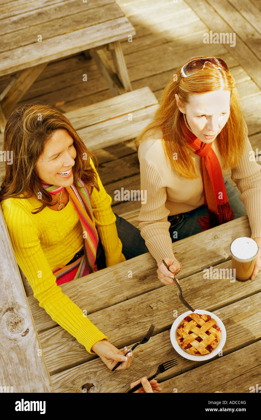 High Angle View Of Two Mature Women Holding Forks And Smiling Stock