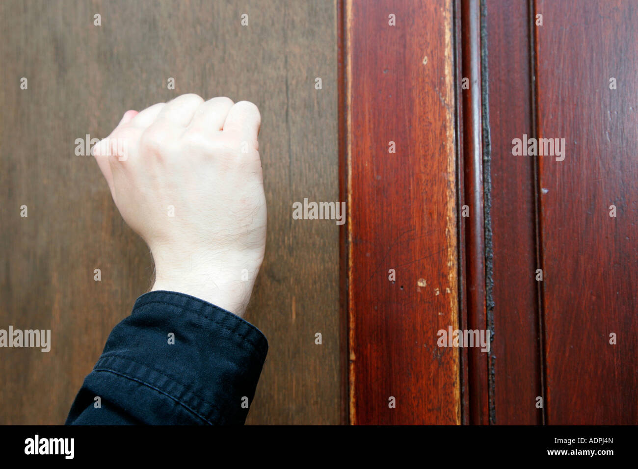 mans bare hand knocking on front door cold calling household Stock
