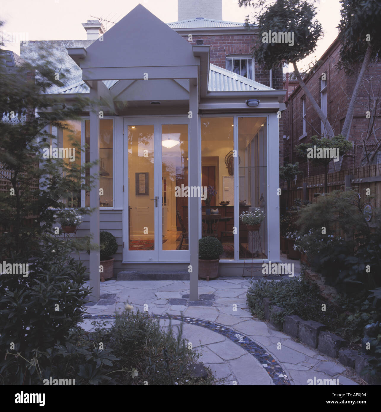 Paved path between borders in small garden of townhouse with glass Paved path between borders in small garden of townhouse with glass